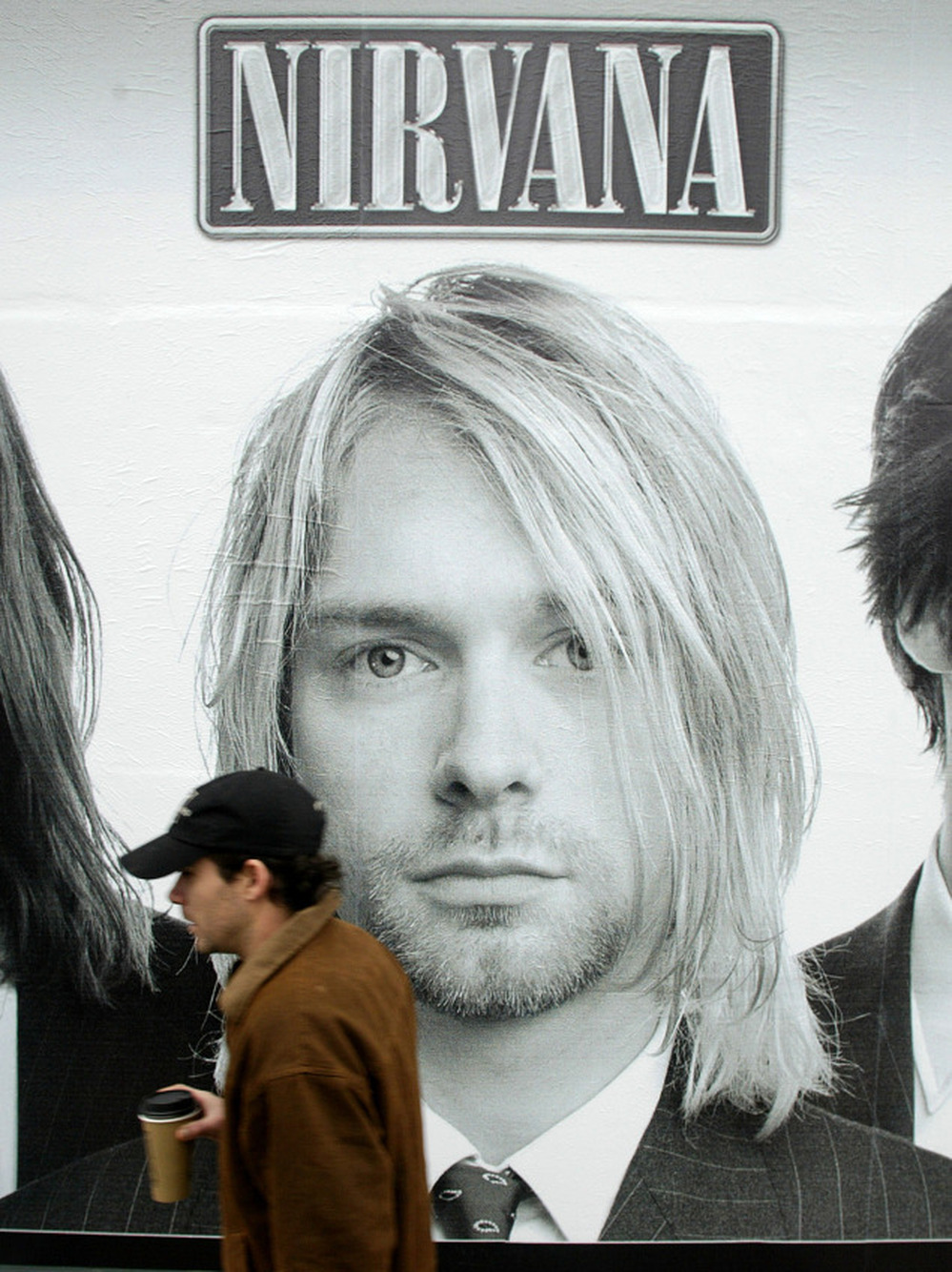 A pedestrian walks past a picture of Kurt Cobain on a mural of the cover the Nirvana box set "With the Lights Out," on Nov. 23, 2004.