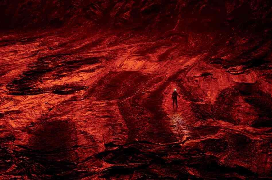 "A member of the expedition walks on the caldera's cooled lava floor, turned red by the reflected glow of the lake. 'Down here you feel the volcano," says photographer Carsten Peter. 'It's a low-frequency rumbling that pulses through your body — like being inside a giant subwoofer.' "