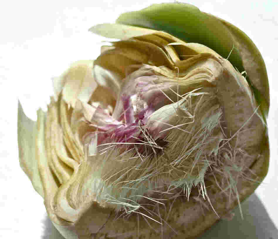 An artichoke sliced in half, exposing the fuzzy choke
