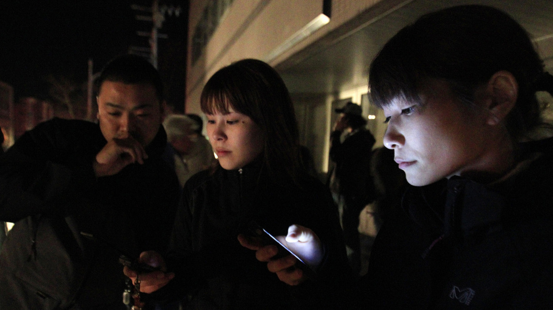 Hotel guests in Ichinoseki, Iwate prefecture, checked their mobile phones for news after they ran outside following a major earthquake that hit Japan on Thursday night.