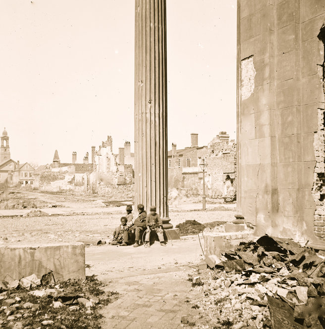 Four freed African-American children sit amid the ruins of Charleston, S.C., in 1865. 