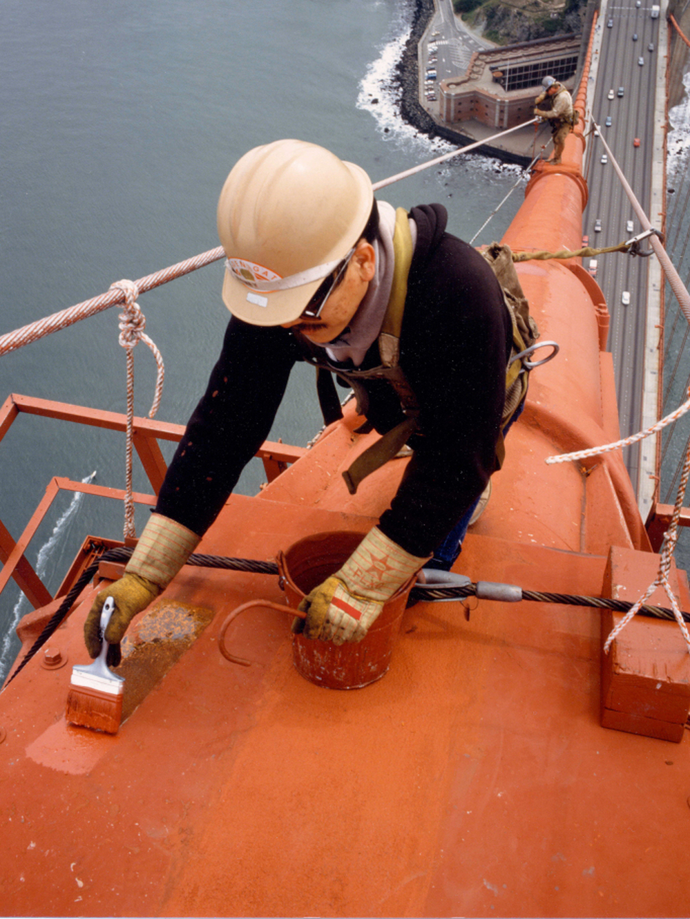 A painter touches up one of the bridge's cables. When it came time to decide the paint color for the bridge, consulting architect Irving Morrow wanted a warm hue to contrast with the cool grays, blues and greens of San Francisco Bay.