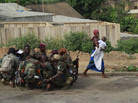 An Abidjan woman passes fighters loyal to Alassane Ouattara as they share a morning meal on Friday, April 8, 2011. An Abidjan woman passes fighters loyal to Alassane Ouattara as they share a morning meal on Friday, April 8, 2011.