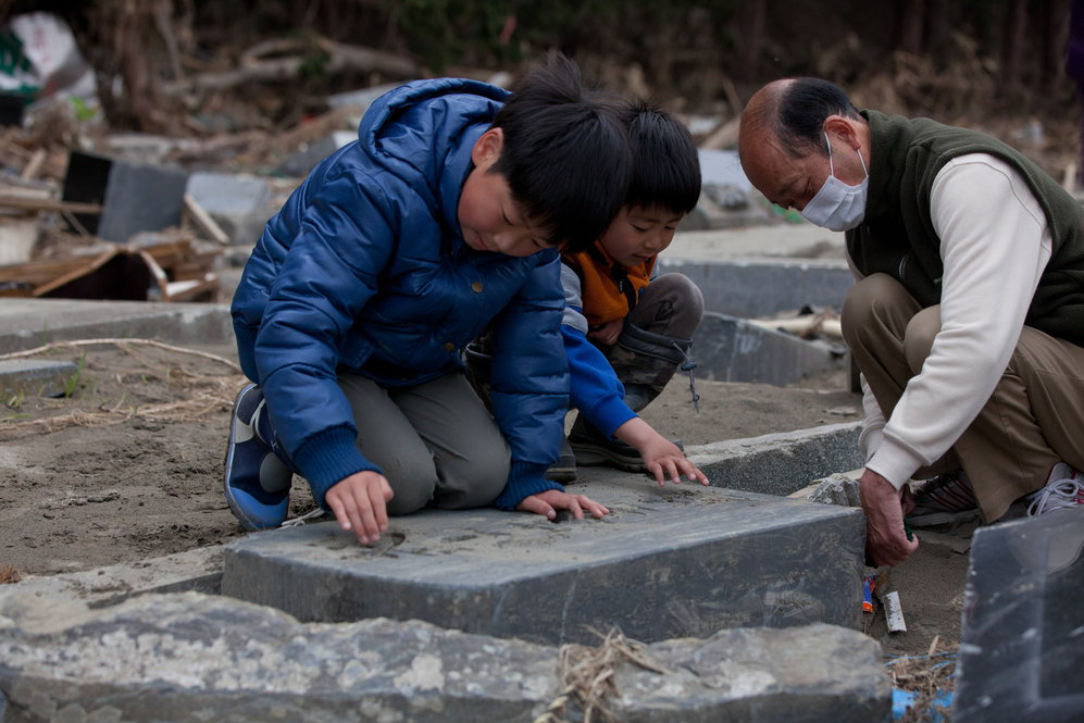 Ren Sato, 9, removes sand from a damaged family grave in Ishinomaki, Miyagi prefecture. 