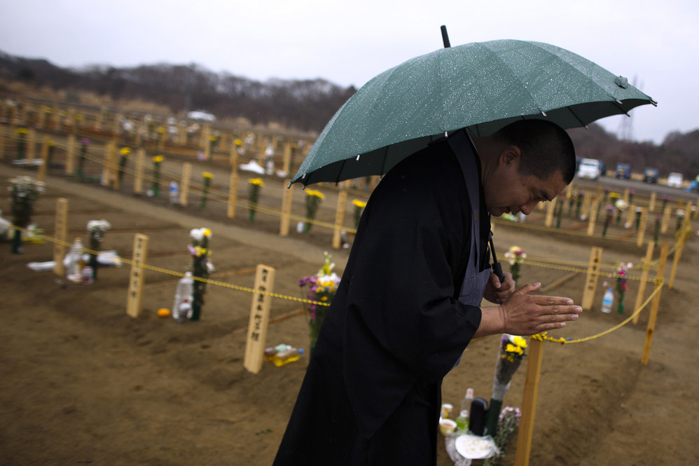 A Buddhist monk prays for earthquake victims at a burial site in Higashimatsushima, Miyagi prefecture. A tsunami warning was issued Monday after a 6.6 aftershock struck south of Fukushima. 