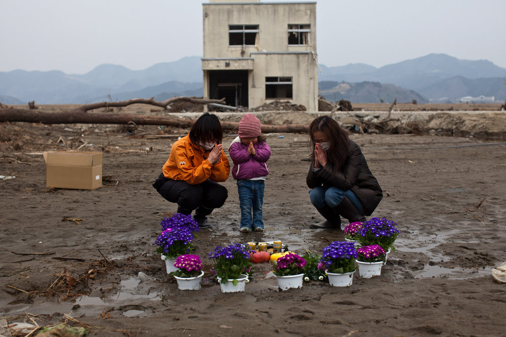 Two-year-old Ayaka (center) and family members pray for her missing grandmother and great-grandmother at a vacant lot where they lived in Ishinomaki, Miyagi prefecture. 