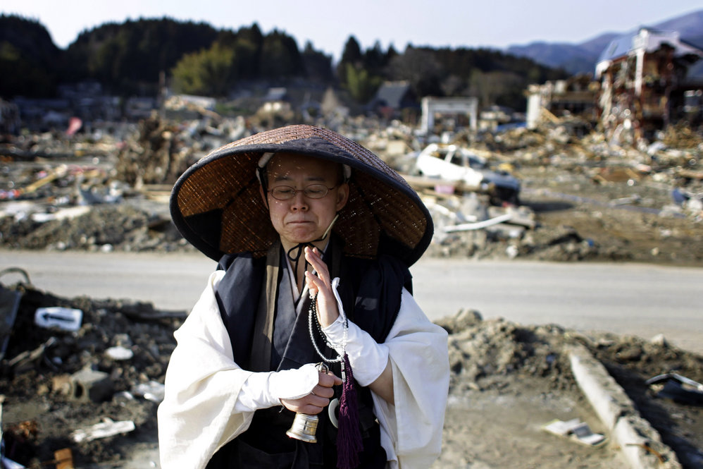 A Japanese Buddhist monk prays at an area devastated by the earthquake and tsunami in Rikuzentakata, Iwate prefecture on Sunday.