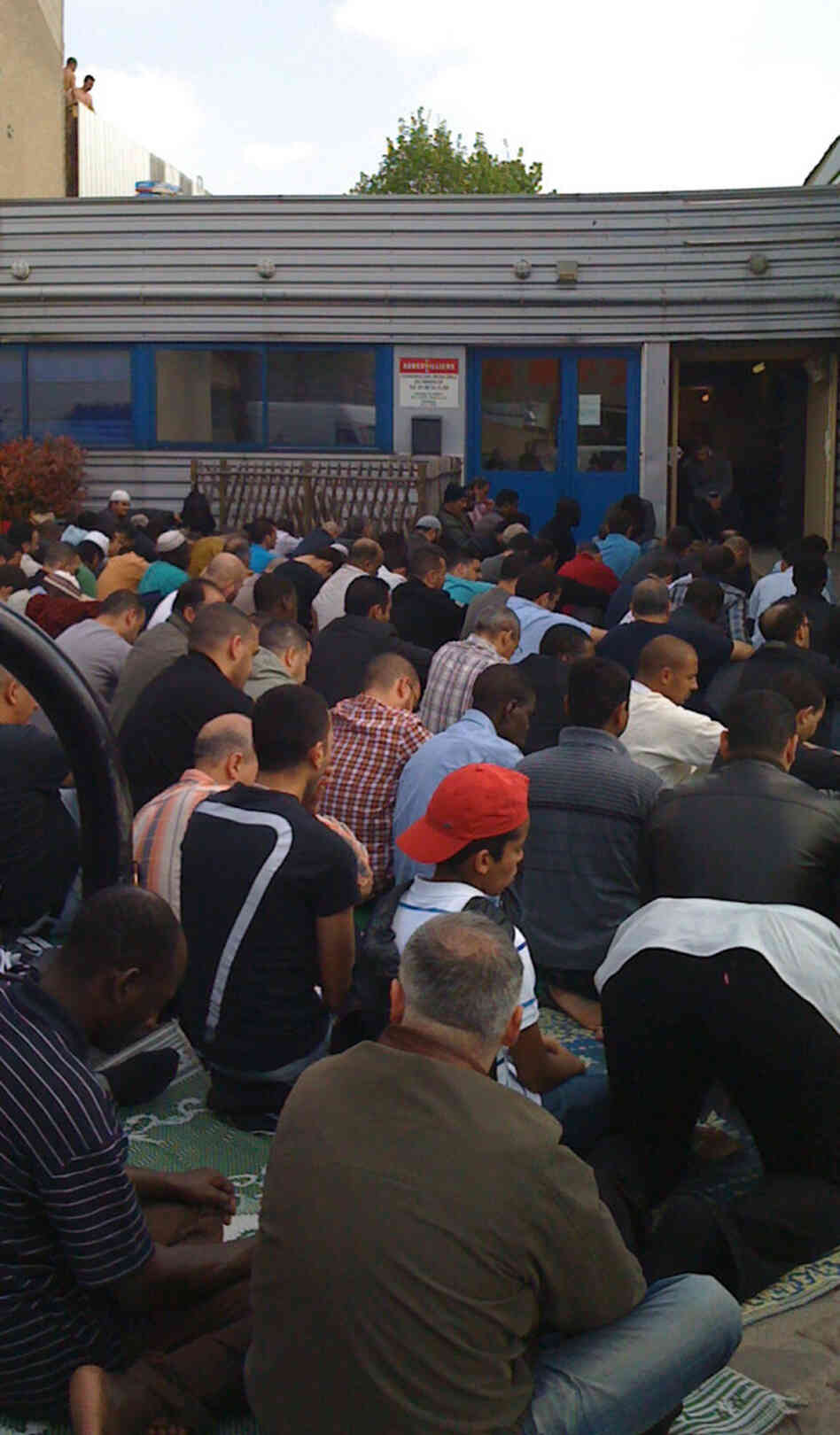 Muslim men gather for Friday prayers outside a makeshift mosque in the Paris suburb of Aubervilliers. The old office building is too small.