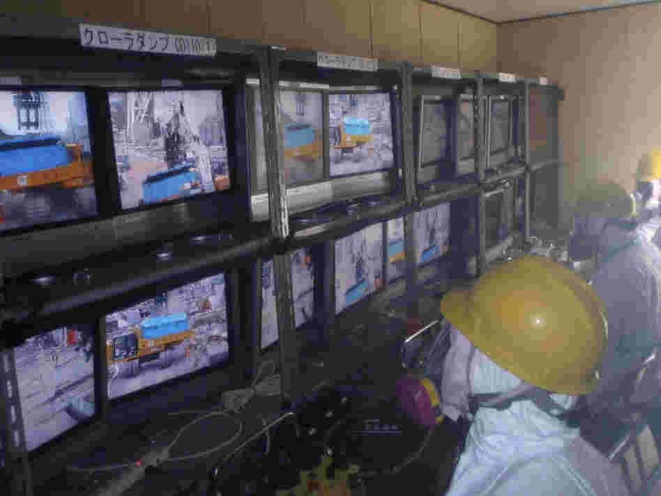 Workers operate remote-controlled rubble-removing equipment at the Fukushima Dai-ichi nuclear complex. Though robotic machines will be able to clear some of the larger debris from the facility, some people will most likely be needed to work inside the reactor buildings.