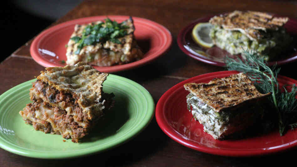 Four plates with slices of a variety of minas, or layered matzo pies (clockwise from upper left): Roman-Inspired Potato, Pea And Artichoke Mina With Gremolata; Leek And Asparagus Mina With Mint And Lemon; Spinach And Feta Mina With Fresh Dill; and Mina De Carne.
