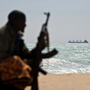 An armed Somali pirate keeps vigil along the coastline of Hobyo, a pirate lair on the Indian Ocean. An armed Somali pirate keeps vigil along the coastline of Hobyo, a pirate lair on the Indian Ocean.