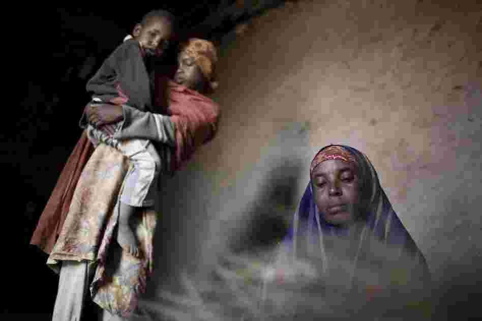 Nimeo weaves a floor mat in her rural home with two of her six children.