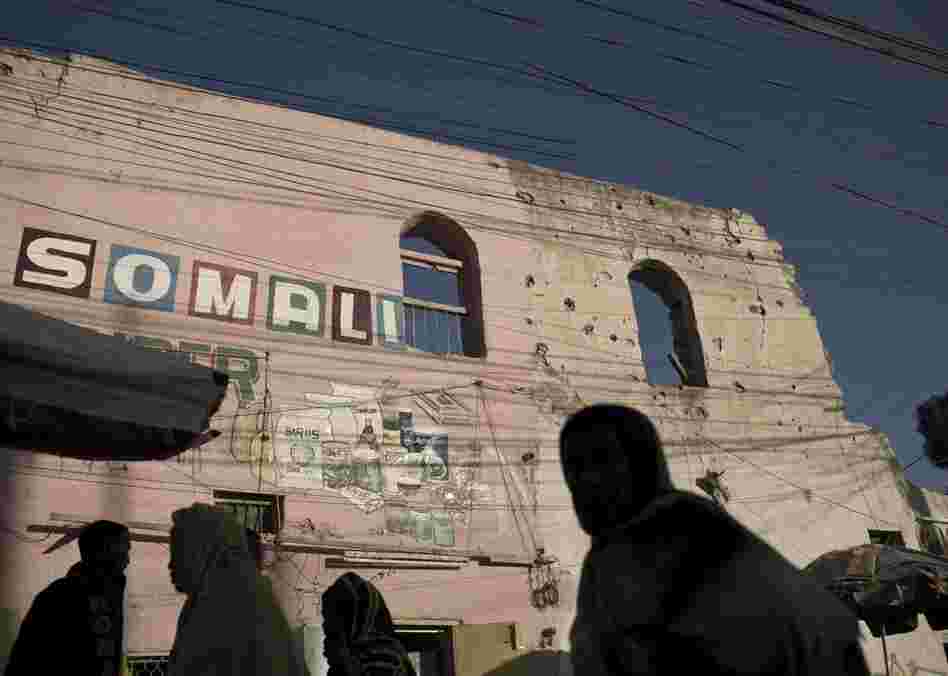Men and women walk through the bustling central market in Hargeisa, passing war-damaged buildings.