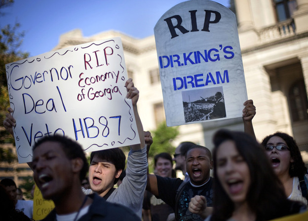 Jason Azurmendi, left, is joined by Will Pesante, center, and Kristen Everett, right, all of Atlanta, as they protest a controversial immigration bill outside the state Capitol Thursday.