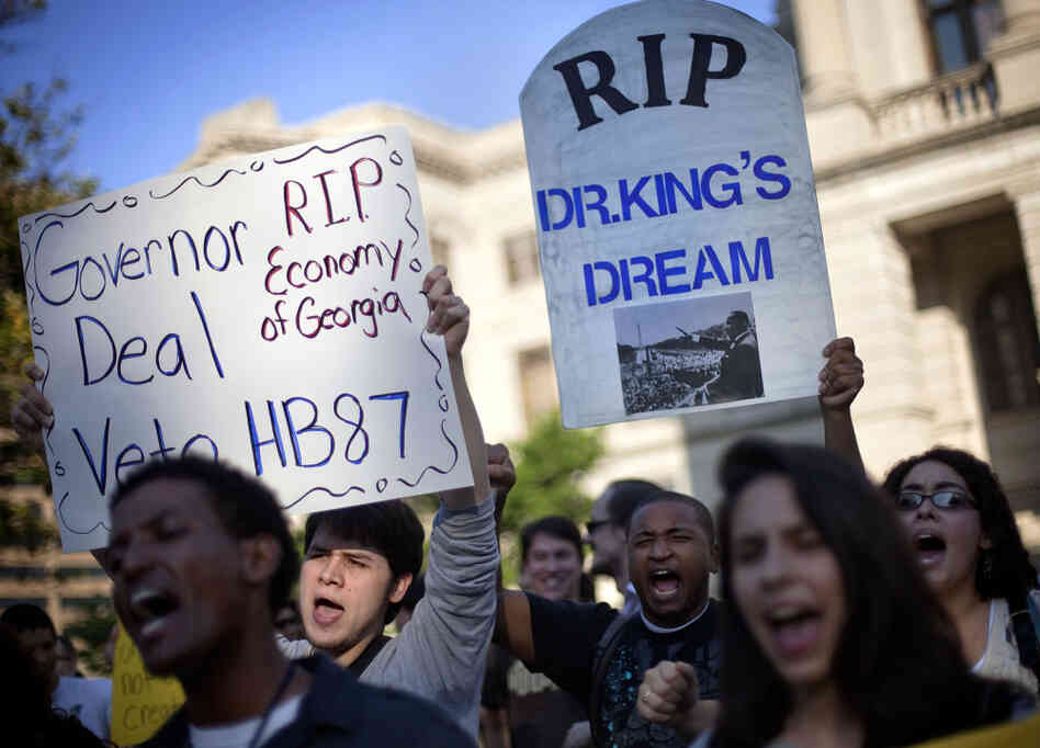 Jason Azurmendi, left, is joined by Will Pesante, center, and Kristen Everett, right, all of Atlanta, as they protest a controversial immigration bill outside the state Capitol Thursday.
