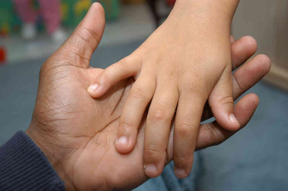 A father and child hold hands. A father and child hold hands.