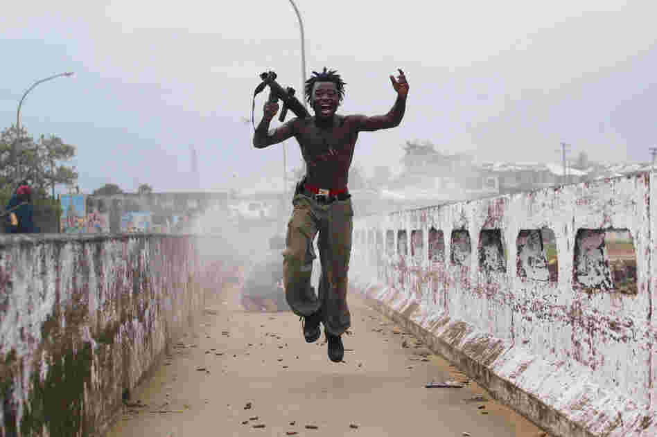 Joseph Duo, a Liberian militia commander loyal to the government, exults after firing a rocket-propelled grenade at rebel forces at a key strategic bridge in Monrovia, Liberia, on July 20, 2003.