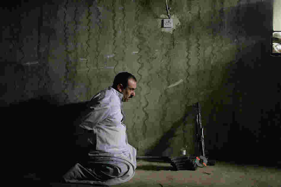 A detained man waits to be photographed by Marines for processing with the weapons allegedly found with him, June 24, 2005, near Fallujah, Iraq.