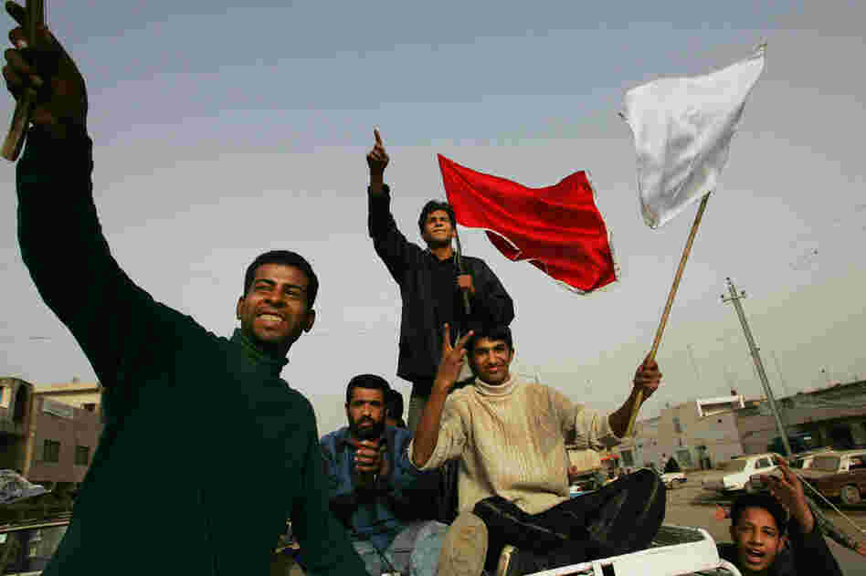 Men brandish flags during a parade celebrating the Shiite festival of Al Ghadeer in the Sadr City neighborhood of Baghdad, Jan. 29, 2005.