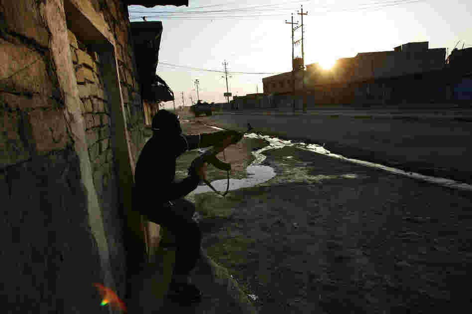 An Iraqi police officer fires at attacking insurgents during a Jan. 16, 2005, firefight in Tal Afar, Iraq. A routine patrol in the insurgent stronghold turned into an hourlong running gun battle with a combined U.S. and Iraqi police force battling insurgents across alleys and down boulevards.
