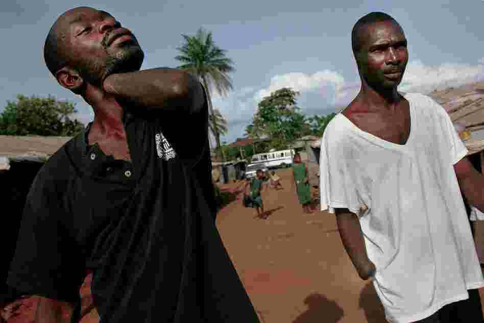 Men missing arms and ears walk around a camp for amputees in Freetown, Sierra Leone, June 5, 2001.