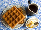 Belgian-style waffles on a plate, with a pitcher of maple syrup and a bowl of orange whipped cream on the side Belgian-style waffles on a plate, with a pitcher of maple syrup and a bowl of orange whipped cream on the side