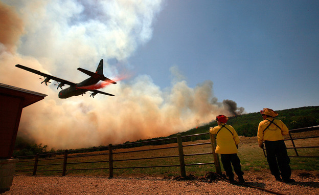 Emergency crews drop a fire retardant slurry on a running wildfire to save a house on April in Strawn, Texas, on Tuesday.