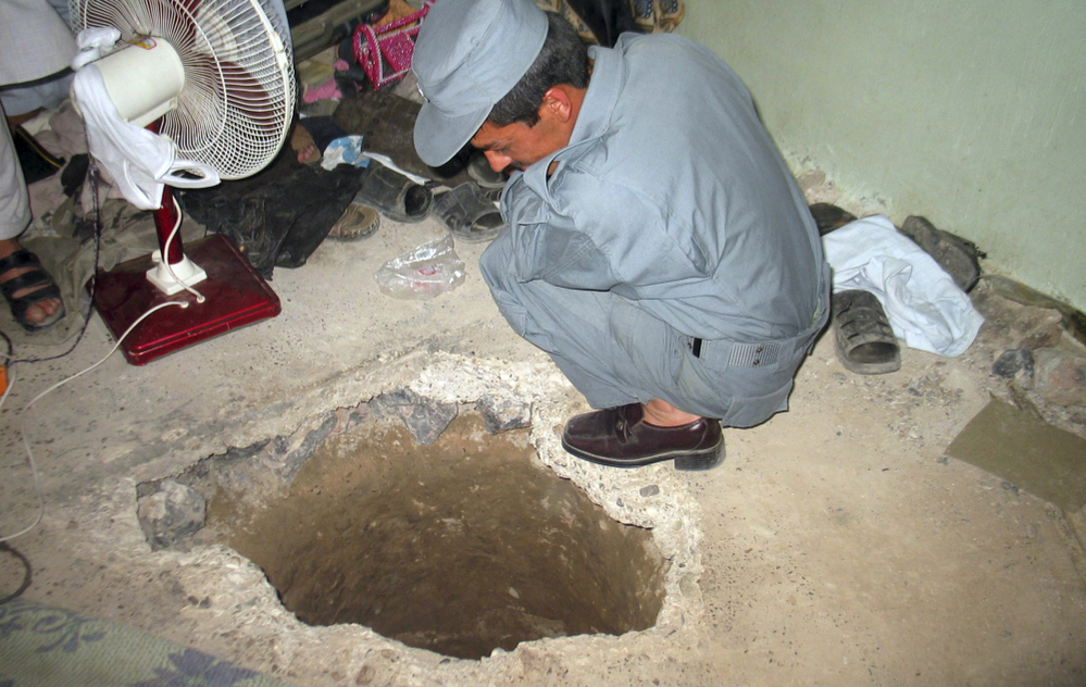 An Afghan policemen peers into the opening of a tunnel at the Sarposa prison in Kandahar city. More than 480 inmates used the 1,000-foot tunnel to escape in a prison break that began late Sunday and early Monday.
