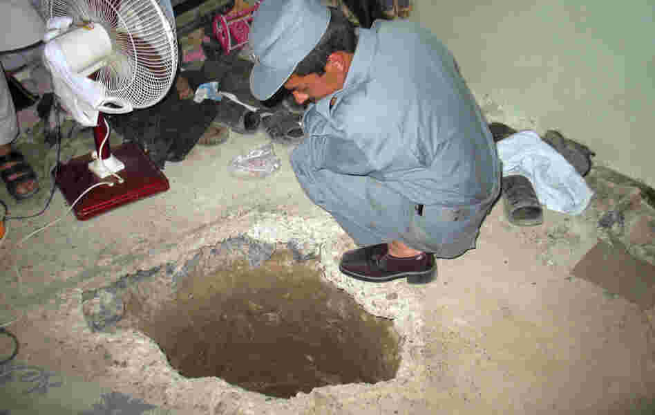 An Afghan policemen peers into the opening of a tunnel at the Sarposa prison in Kandahar city. More than 480 inmates used the 1,000-foot tunnel to escape in a prison break that began late Sunday and early Monday.