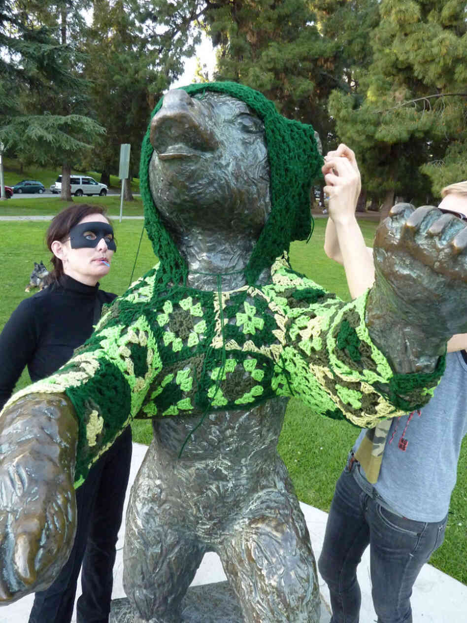 Captain Hook (left) and her accomplice, Vanessa XKiller, vandalize a bear statue in L.A.'s Griffith Park in the most cozy way possible: with a hand-crocheted hoodie. Stepping back to assess their handiwork, Vanessa concludes, it's "gangster cute."