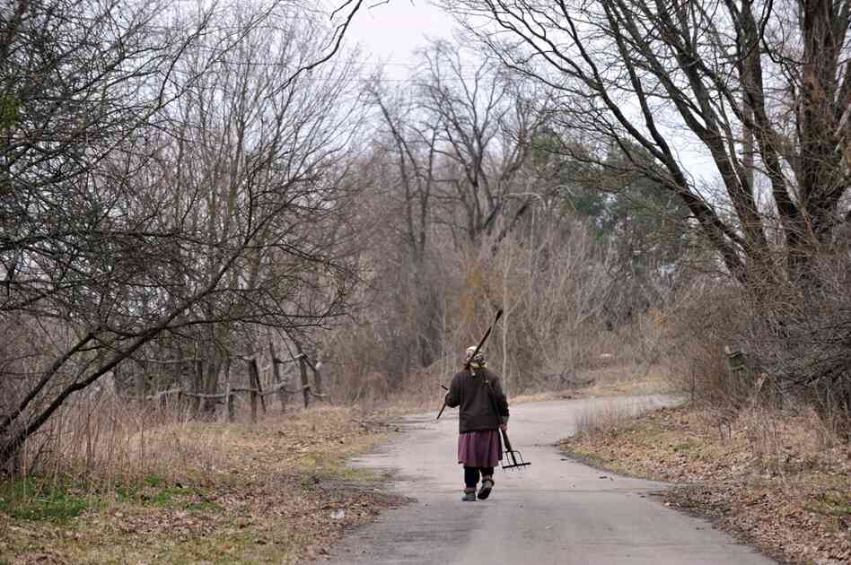 Ganna Zavorotnya, 78, carries her tools as she walks to her vegetable garden in Kupovate, inside the exclusion zone, in April 2011. 