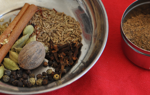 A bowl containing components of garam masala spice, and a bowl of the ground spices