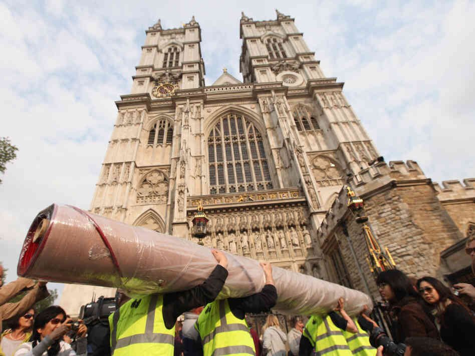 Workers carry in sections of the red carpet at Westminster Abbey where Prince William and Kate Middleton are scheduled to get married tomorrow.