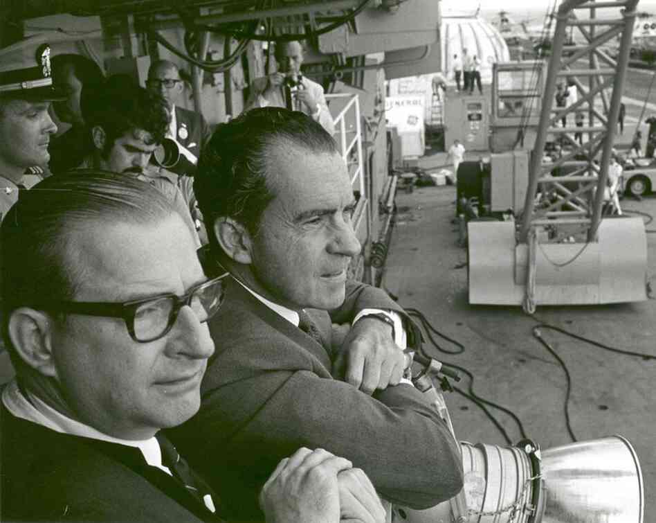 President Richard Nixon (right) and NASA Administrator Thomas O. Paine, aboard the USS Hornet, watch the Apollo 11 astronauts walk from the recovery helicopter to a quarantine facility on the ship on July 24, 1969. 