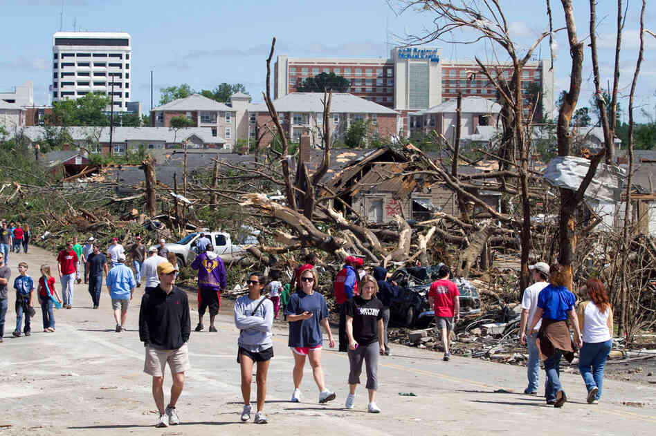 Residents wander the streets near downtown Tuscaloosa surveying the damage on Thursday. President Obama is headed to the area today. The tornado that touched down in Tuscaloosa was estimated to be one mile wide.  