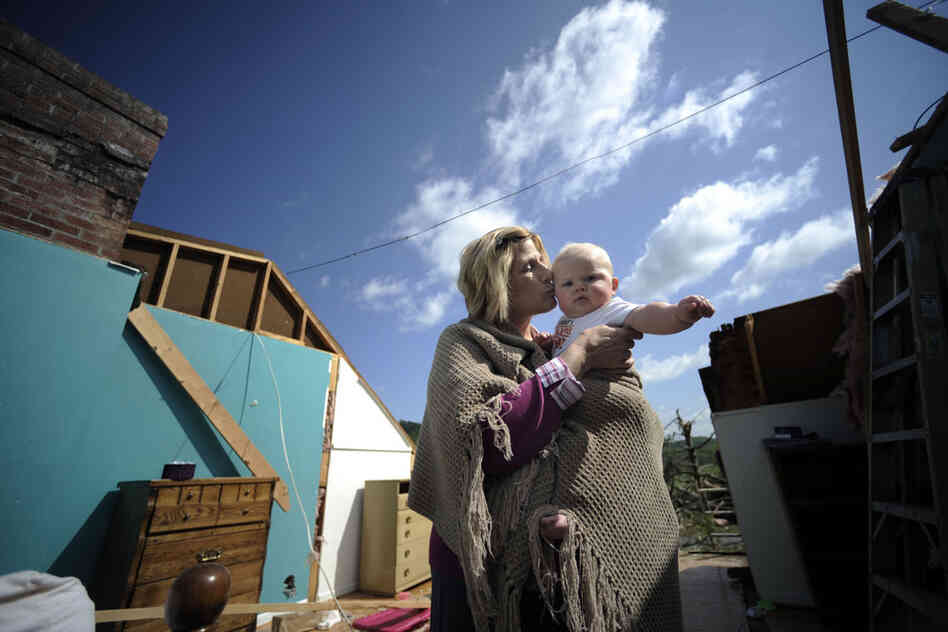 Gail Gilland, 58, holds her 6-month-old grandson, Major Sealey, amid the wreckage of her home in Bethel, Va., Friday. Gilland survived a tornado early Thursday morning by hiding under her bed and riding out the storm while her husband, James, was trapped in the hallway. 