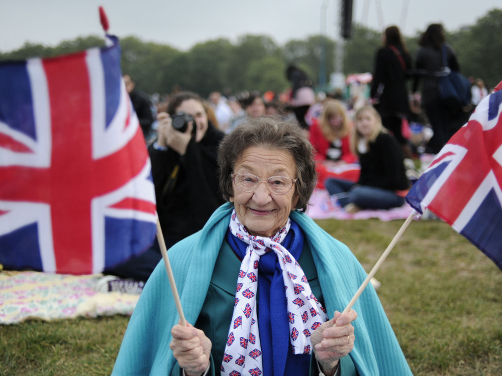 A fan holds British Union Jack flags as people gather to watch the wedding of Britain's Prince William and Kate Middleton on big screens in Hyde Park in central London.