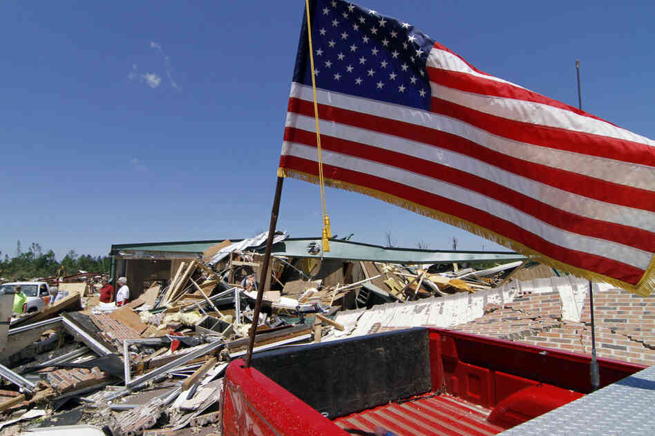 An American flag flies atop a destroyed pickup truck outside the remains of the town hall in Smithville, Miss. 
