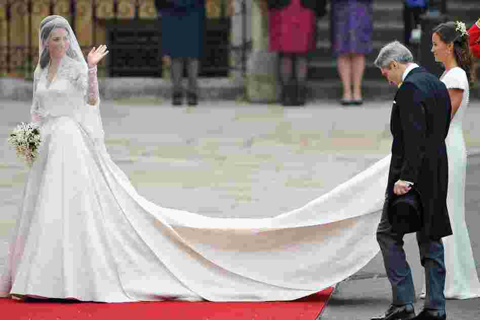 Kate Middleton waves to the crowds as her sister, Pippa, holds her dress next to her father, Michael, before entering Westminster Abbey. 