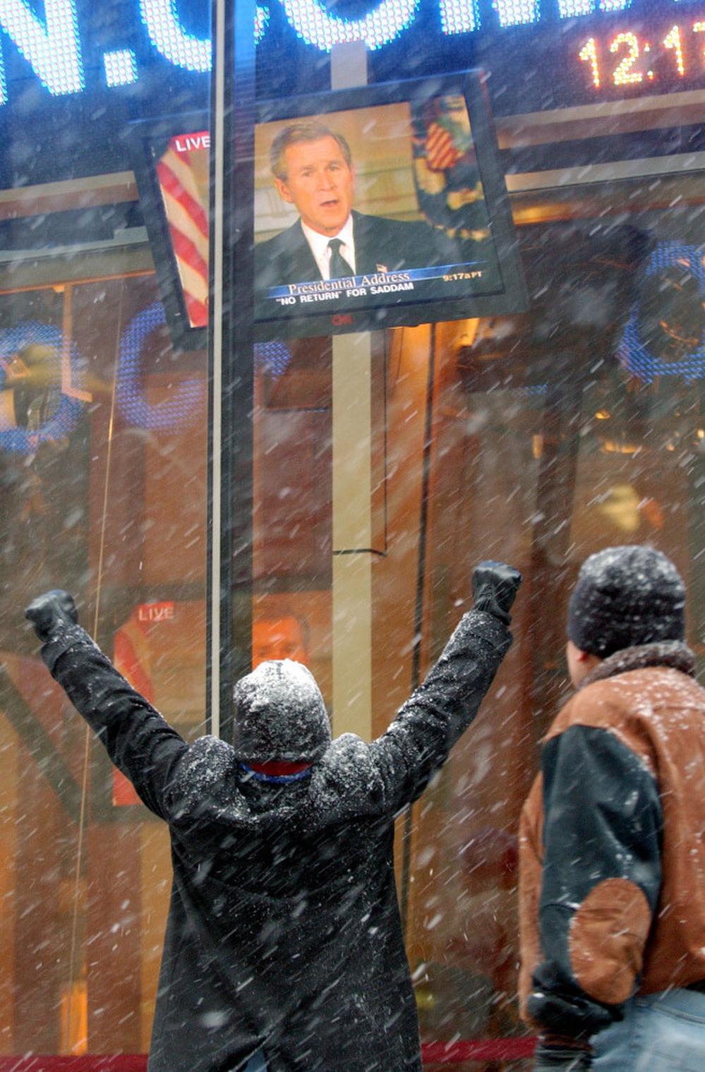 A New York City pedestrian raises his arms in a victory gesture as he watches President George W. Bush announce the capture of Saddam Hussein, Dec. 14, 2003.
