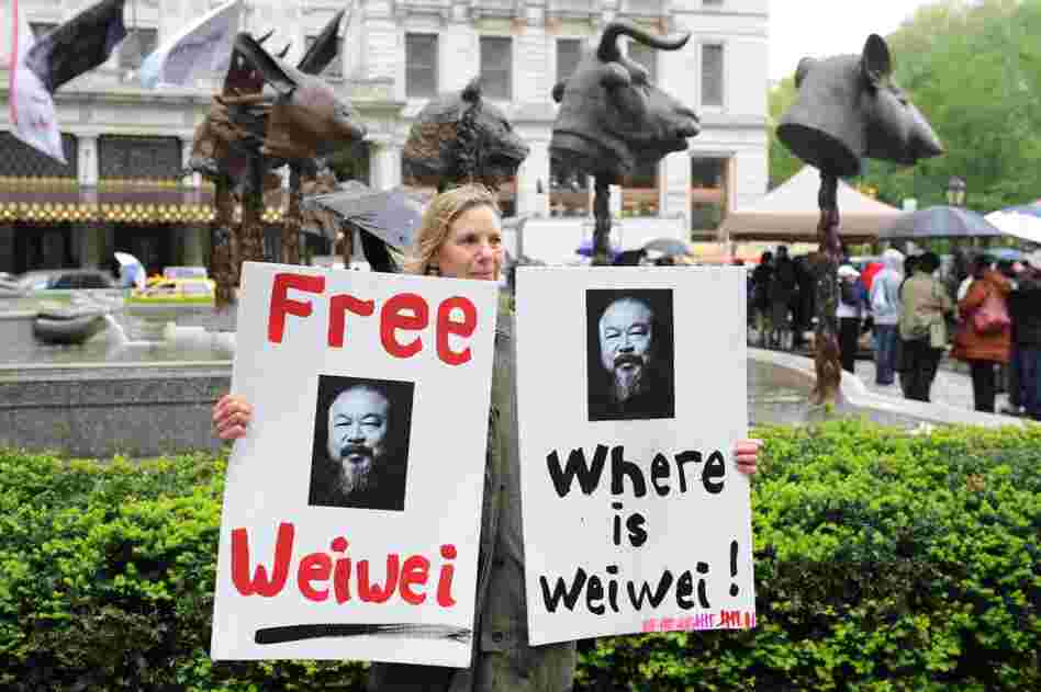 Susan Henoch holds signs in front of the installation. Ai has been missing since his arrest a month ago in Beijing.  