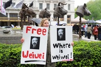 Susan Henoch holds signs in front of the installation. Ai has been missing since his arrest a month ago in Beijing.