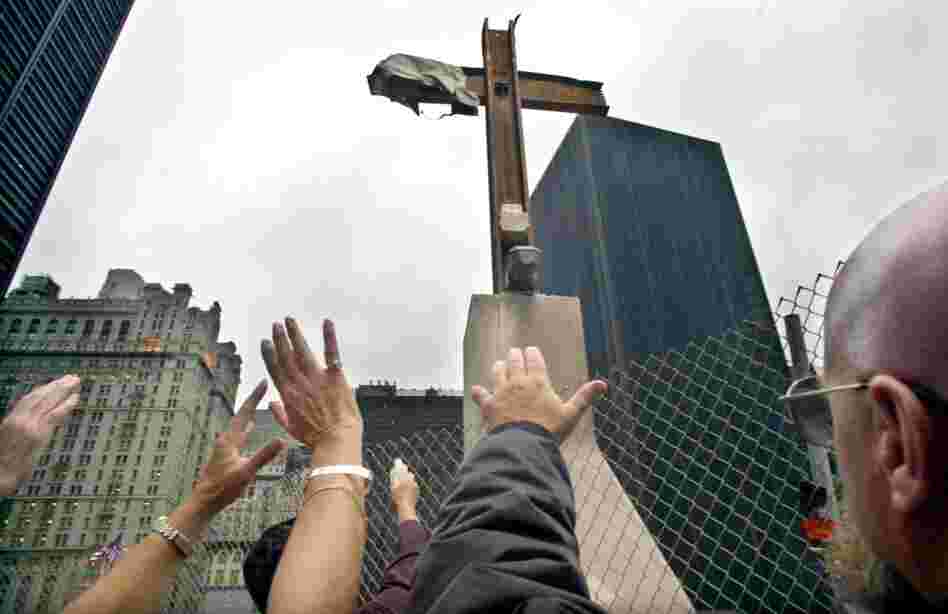 The Rev. Brian Jordan (with bottle) applies holy water to a steel beam cross during its rededication at the World Trade Center site in New York, Oct. 3, 2002. 