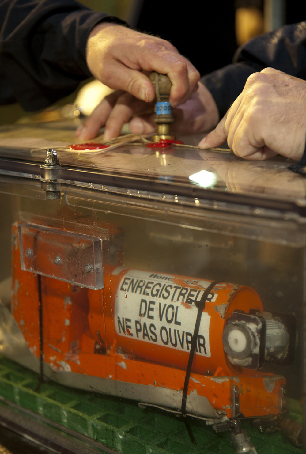Investigators hold the sealed flight data recorder recovered from the crashed Air France Flight 447.