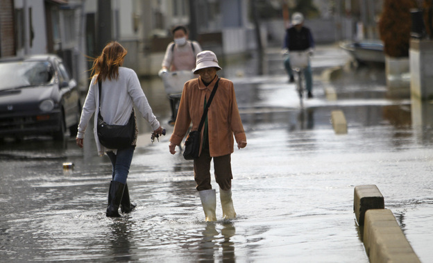 Residents stroll in a flooded street in Ishinomaki, Miyagi Prefecture, Japan. The area in this part of the city sunk nearly 2 feet 7 inches following the March 11 earthquake and tsunami.