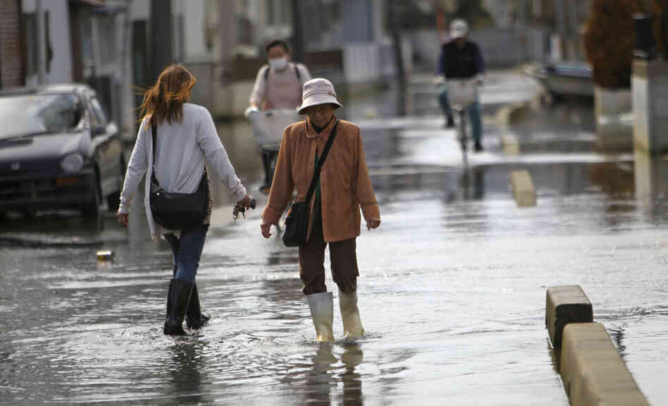 Residents stroll in a flooded street in Ishinomaki, Miyagi Prefecture, Japan. The area in this part of the city sunk nearly 2 feet 7 inches following the March 11 earthquake and tsunami.