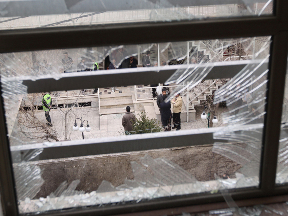 Iranian security agents are seen through a shattered window after Iranian nuclear engineer Massoud Ali Mohammadi was killed outside his Tehran residence when a booby-trapped motorcycle exploded on Jan. 12, 2010.