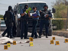 Mexican police agents look at a man's corpse on a street of Ciudad Juarez, Mexico, on October 4, 2010. Host Neal Conan talks about Mexico's brutal drug wars in the second hour. Mexican police agents look at a man's corpse on a street of Ciudad Juarez, Mexico, on October 4, 2010. Host Neal Conan talks about Mexico's brutal drug wars in the second hour.