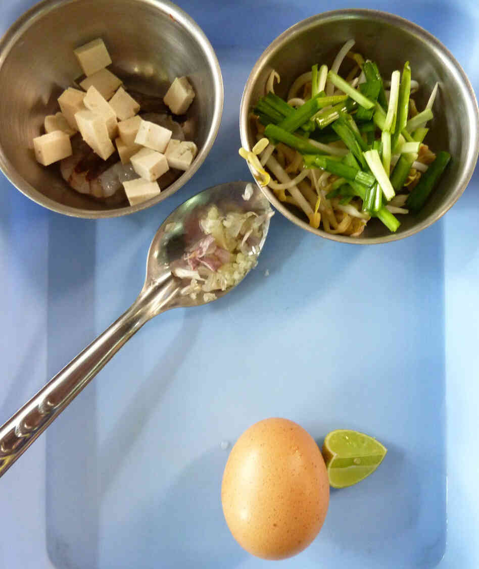 Ingredients for making Pad Thai (Thai Fried Noodles) include diced tofu and spring onions, crushed garlic, egg and lime.