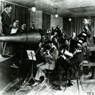The Victor Orchestra crowds around an enormous horn for an early acoustical recording session.